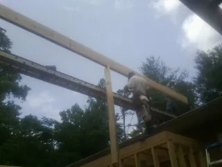 Carpenter setting a ridge beam over a new addition frame — Ice Dam Removal by Roofing Brothers in Emory