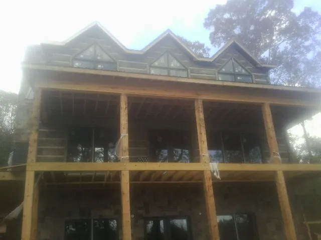Dormers and porch framing on a large log home under construction — Roof Coating work by our crew in Emory