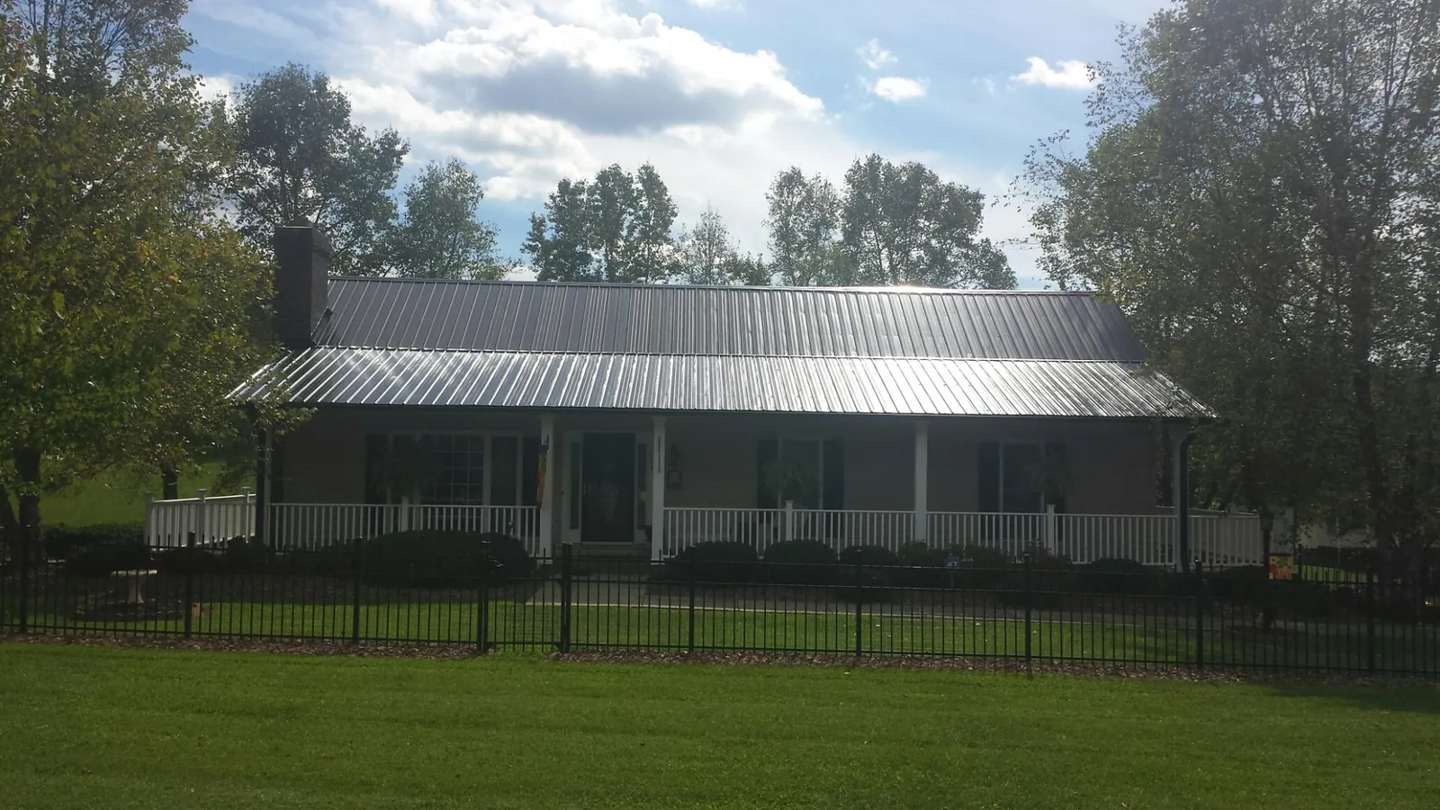 Gray metal roof on a brick ranch with a full width front porch — Gutter Guard Installation work by our crew in Emory