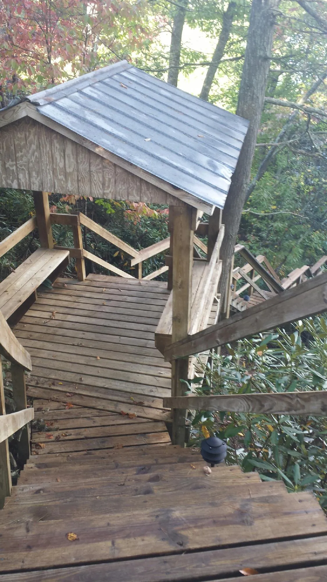 Metal roofed shelter over wooden steps on a wooded walkway — Skylight Repair & Installation work by our crew in Emory